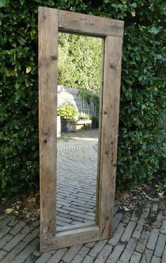 a wooden mirror sitting on top of a brick walkway