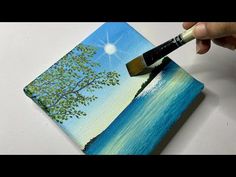 someone is painting a tree on a piece of paper with a paintbrush in their hand