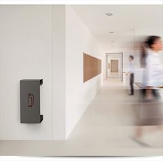 two people walking down a long hallway with a red and white sign on the wall