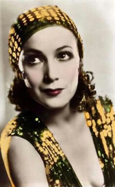 an old photo of a woman wearing a yellow and green dress with gold sequins on her head