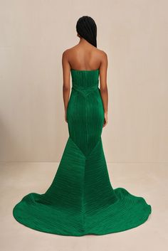 A sculpturally designed plissé strapless gown featuring a exaggerated train and artful bust. — Sculpted plissé fabric — Rose bud shaped bust details — Exaggerated train — Mermaid tail hem Plisse Fabric, Fabric Rose, And July, Fabric Roses, Rose Bud, Swimming Bag, Strapless Gown, Candle Collection, Autumn Sales