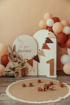 a rabbit sitting on the floor in front of a wooden block set with letters and balloons