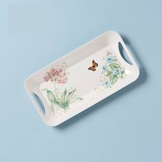 a white tray with flowers and butterflies painted on the side, against a blue background