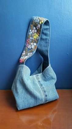 a purse made out of old jeans on a wooden table next to a blue wall