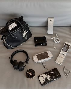 a purse, cell phone, headphones and other items are laid out on a bed