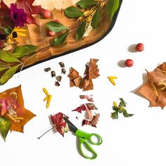 fall leaves and scissors on a table with other autumn crafting supplies including paper flowers, leaves, and acorns