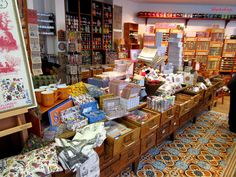 a store filled with lots of boxes and other items on top of wooden tables in front of shelves