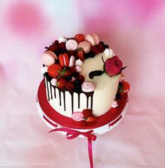 a white and red cake with chocolate icing, strawberries and roses on top