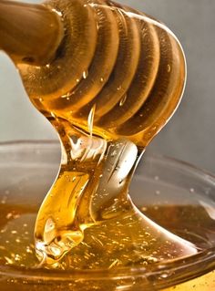 honey is being poured into a glass bowl