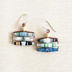 This eco friendly pair of earrings is made of paper beads handcrafted from a travel magazine. The dangles are aesthetically put together in charming shades of blue and brown. The paper beads are given a coat of eco friendly sealant to make them water resistant.The beads are strung through a brown waxed cotton cord, with a little wooden bead at the top. The dangles hang from hand formed sterling silver ear wires.My jewelry making process is incredibly time consuming and tedious, however, the fina Earthy Earrings, Recycled Earrings, Garden Magazine, Clean Gold Jewelry, Garden Lover Gifts, Boho Chic Necklace, Paper Bead Jewelry, Earthy Jewelry, Fair Trade Jewelry