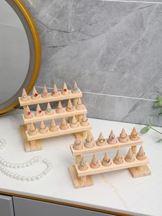 two wooden pegs are stacked on top of each other near a necklace and mirror