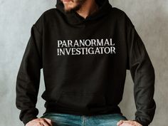 a man wearing a black hoodie with the words paranomal investigator printed on it