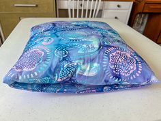 a blue and pink pillow sitting on top of a white countertop next to a chair