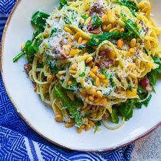 a white plate topped with pasta and veggies on top of a blue table cloth