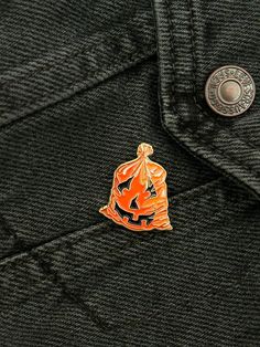 an orange and black pin sitting on top of a jacket