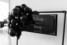 black and white photo of welcome sign with balloons