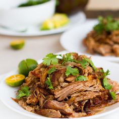 an easy crockpot carnitas recipe on a white plate with cilantro