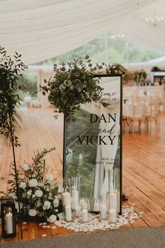 a sign that says dan and vicky on it next to candles, flowers and greenery