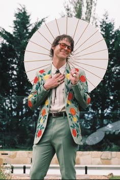 a man in a suit and sunglasses holding an umbrella over his head while standing outside