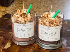 two glasses filled with desserts on top of a wooden table next to each other