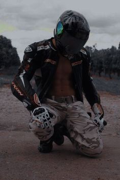 a shirtless man in camouflage gear crouches on the ground