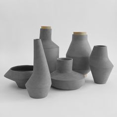 several gray vases sitting next to each other on a white surface