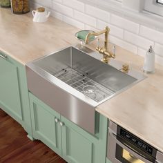 a stainless steel sink in a kitchen with green cabinets and wood flooring on the counter