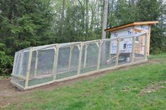 a chicken coop in the middle of a field with trees behind it and a sign on top