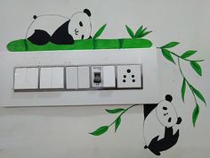 a panda bear is sitting on top of a light switch box with green leaves painted on it