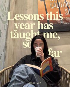 a woman sitting in a chair reading a book and drinking from a cup while holding a coffee mug