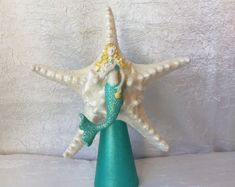 there is a starfish on top of a vase with a mermaid doll in it