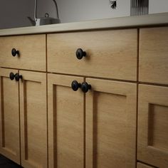 the cabinets are made of wood and have knobs on them, as well as black handles