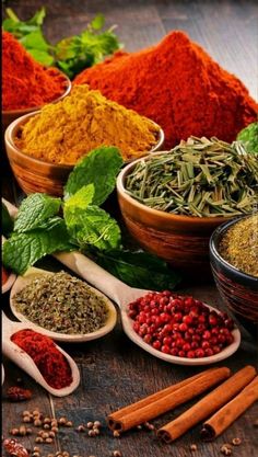 many different types of spices in bowls and spoons