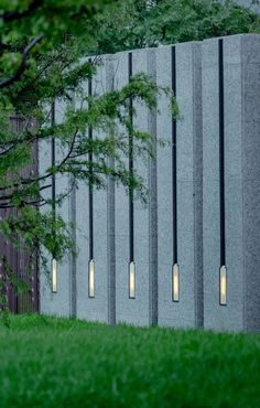 a concrete wall with four lights on it and a tree in the foreground next to it