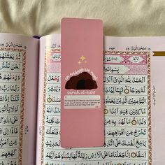 an open pink book with arabic writing on the pages and a cloud in the middle