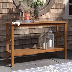 a wooden table with flowers and candles on it in front of a house near a door