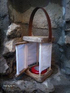 a wooden box with two white curtains and a red object in it