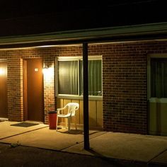 a white chair sitting in front of a brick building at night with the lights on