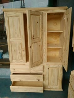 an unfinished wooden armoire sitting on top of a floor next to other pieces of furniture