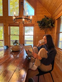 a woman sitting at a table in front of a laptop computer and holding a cup