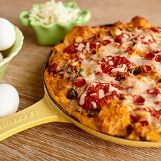 a pizza sitting on top of a pan next to an egg in a green bowl