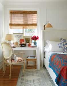 a bedroom with a bed, desk and chair next to a window covered in blinds