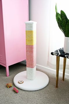 a tall white vase sitting on top of a floor next to a pink cabinet