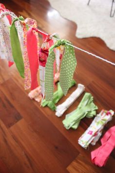 clothes hanging on a line in the middle of a room with wooden floors and white rugs