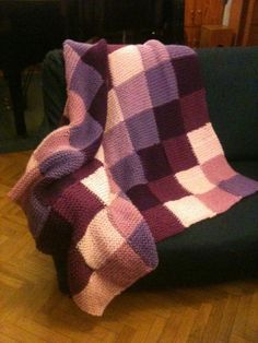 a purple and white blanket sitting on top of a couch