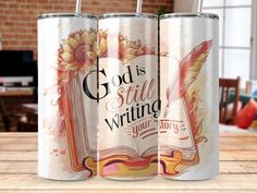 three metal cans with the words god is still writing and an open book on them