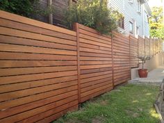 a wooden fence in front of a house with potted plants on the other side