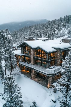 this is an aerial view of a house in the mountains covered in snow and surrounded by trees