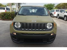 the front end of a green jeep parked in a parking lot