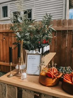 a wooden table topped with vases filled with flowers and fruit on top of it